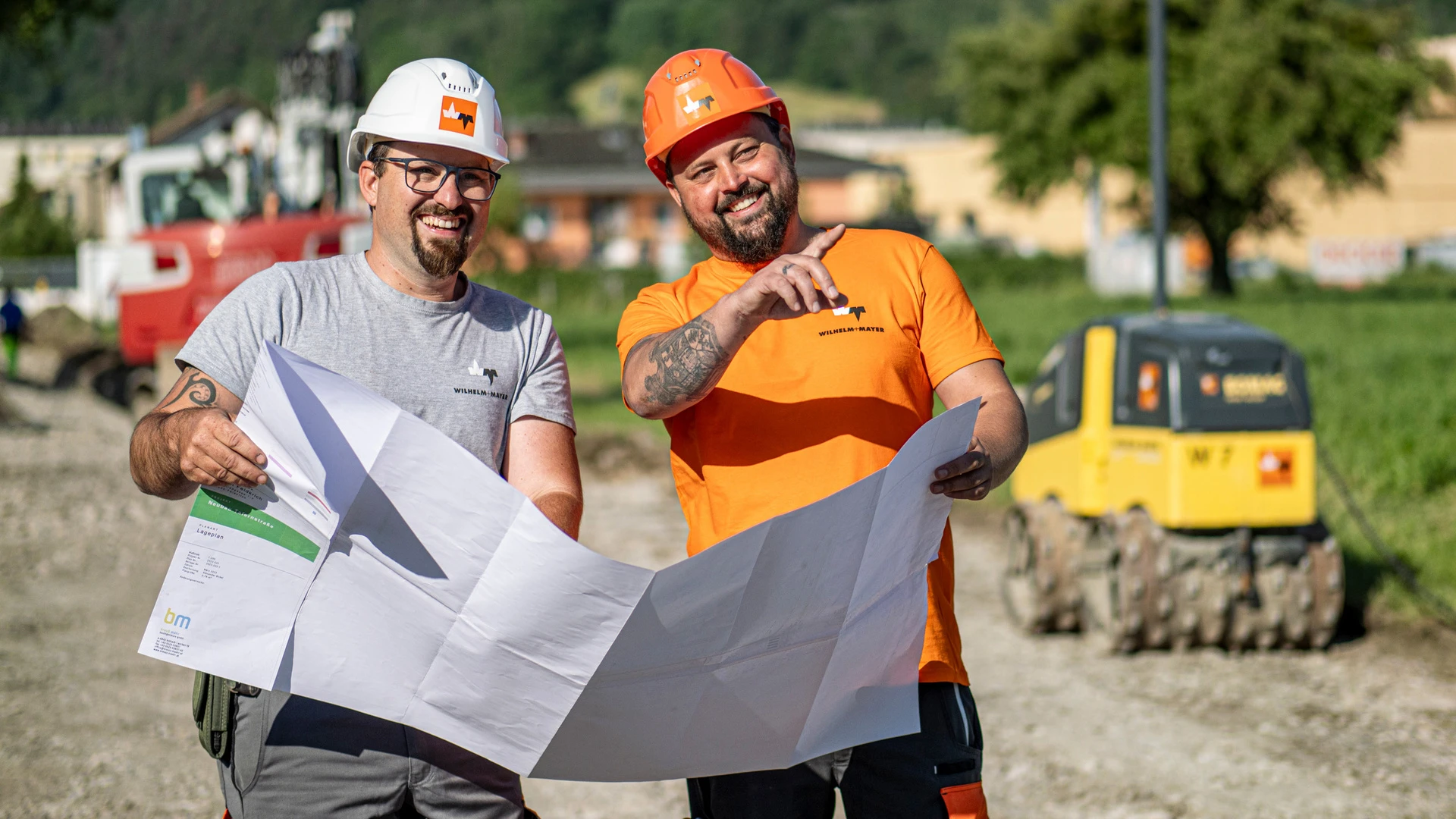 Poliere lachen mit Bauplan in der Hand