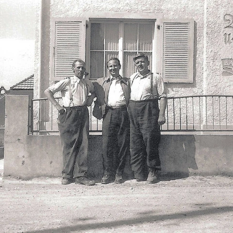 Hugo Wilhelm und Erwin Mayer posieren vor dem gemeinsamen Wohn- und Geschäftshaus für die Kamera. 