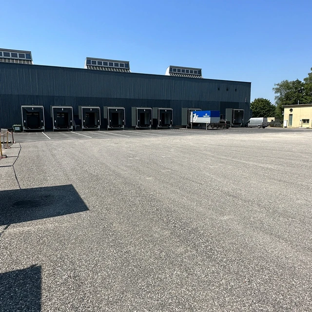 Neu asphaltiertes Betriebsgelände. Logistikhalle mit Laderampen für LKW.