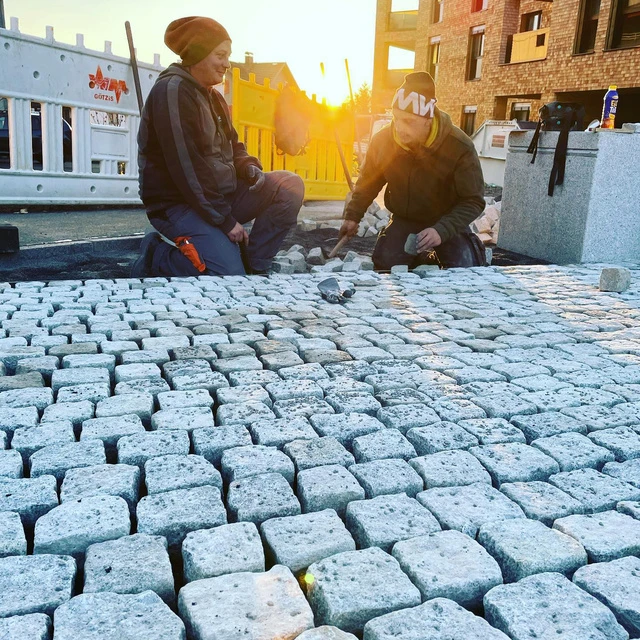 Zwei Arbeiter von Wilhelm und Mayer setzen Pflastersteine.