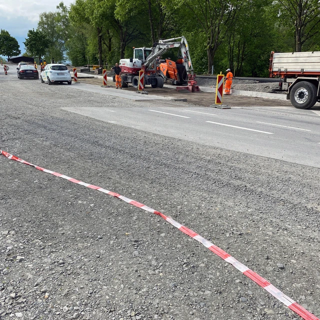 Bagger und LKW samt Arbeiter beim Straßenbau.