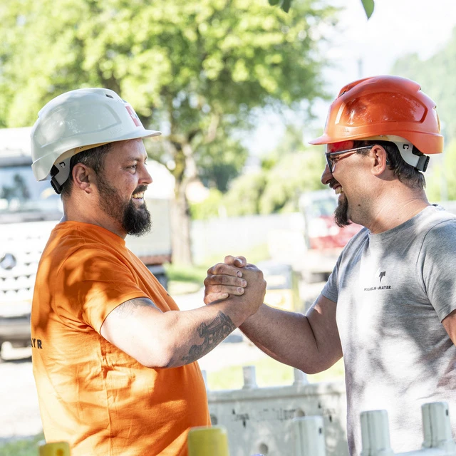 Zwei Bauarbeiter halten sich die Hand als Zeichen der Freundschaft.