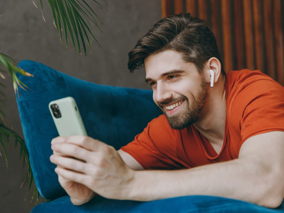 Mann schaut auf sein Smartphone und lächelt.