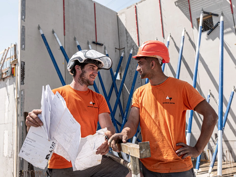 Zwei Bauarbeiter schauen sich an und lachen