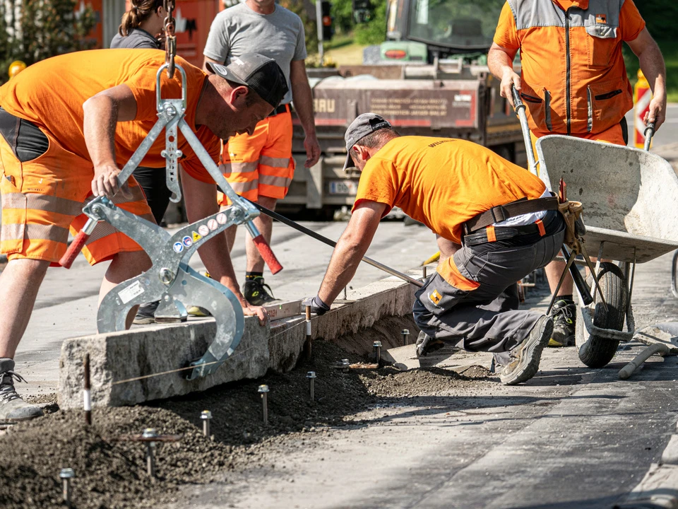 Bauarbeiter setzen Randsteine bei einer Brücke